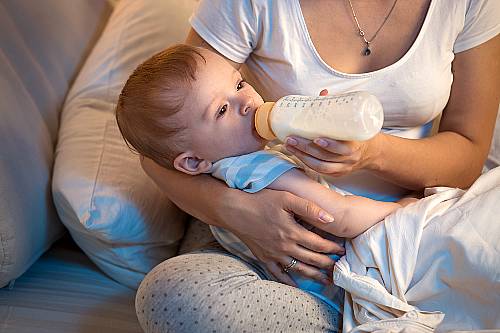 Mama karmi dziecko butelka po odstawieniu od karmienia piersią.